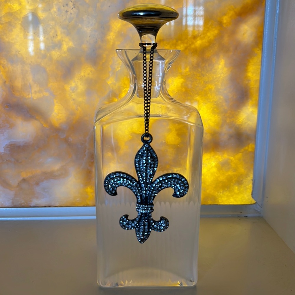 Glass decanter with a silver top. Rhine stone fleur de lys ornament charm.
